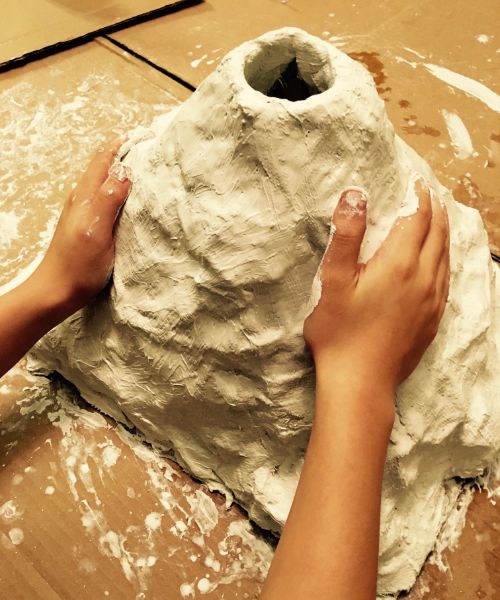 Child constructing a volcano model for a hands-on science lesson