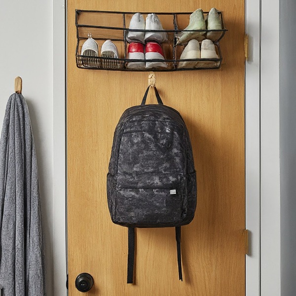 Student hanging backpack on command hook on dorm room door with shoe organizer