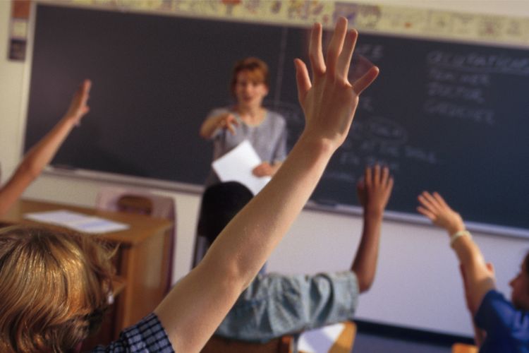 Students raising hands in class, eager to participate in discussions