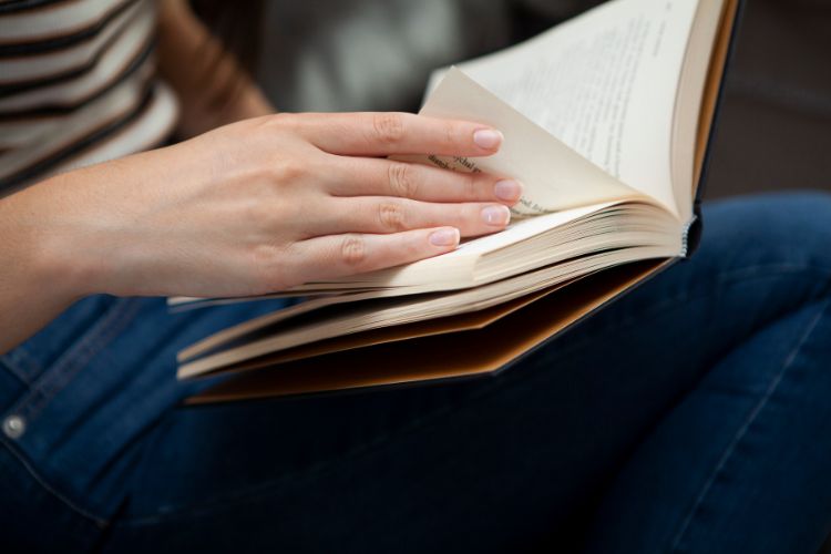 Student's hand turning the pages of a classic novel