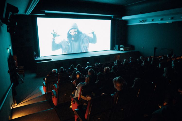 Students anxiously watching a horror film in a dark theater